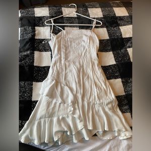 Short white dress with open back and ruffles on bottom